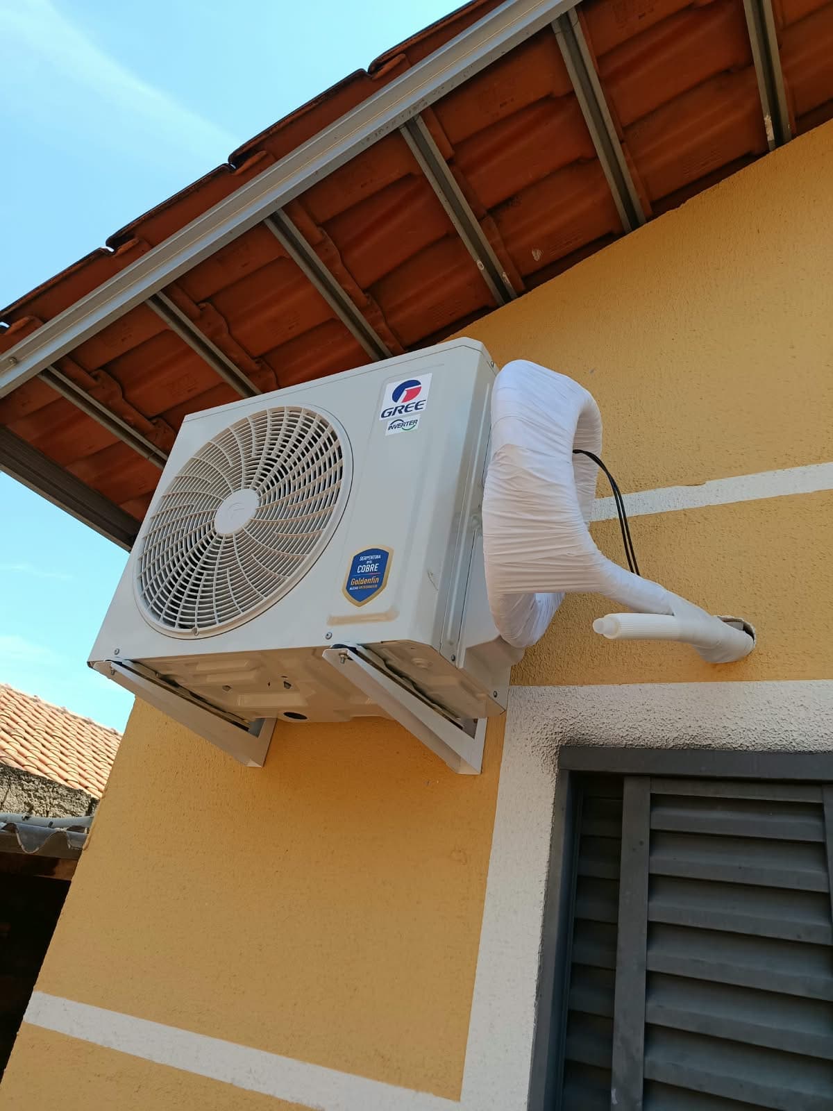 Condensadora de split recém-instalada na parede externa, com a tubulação encapada